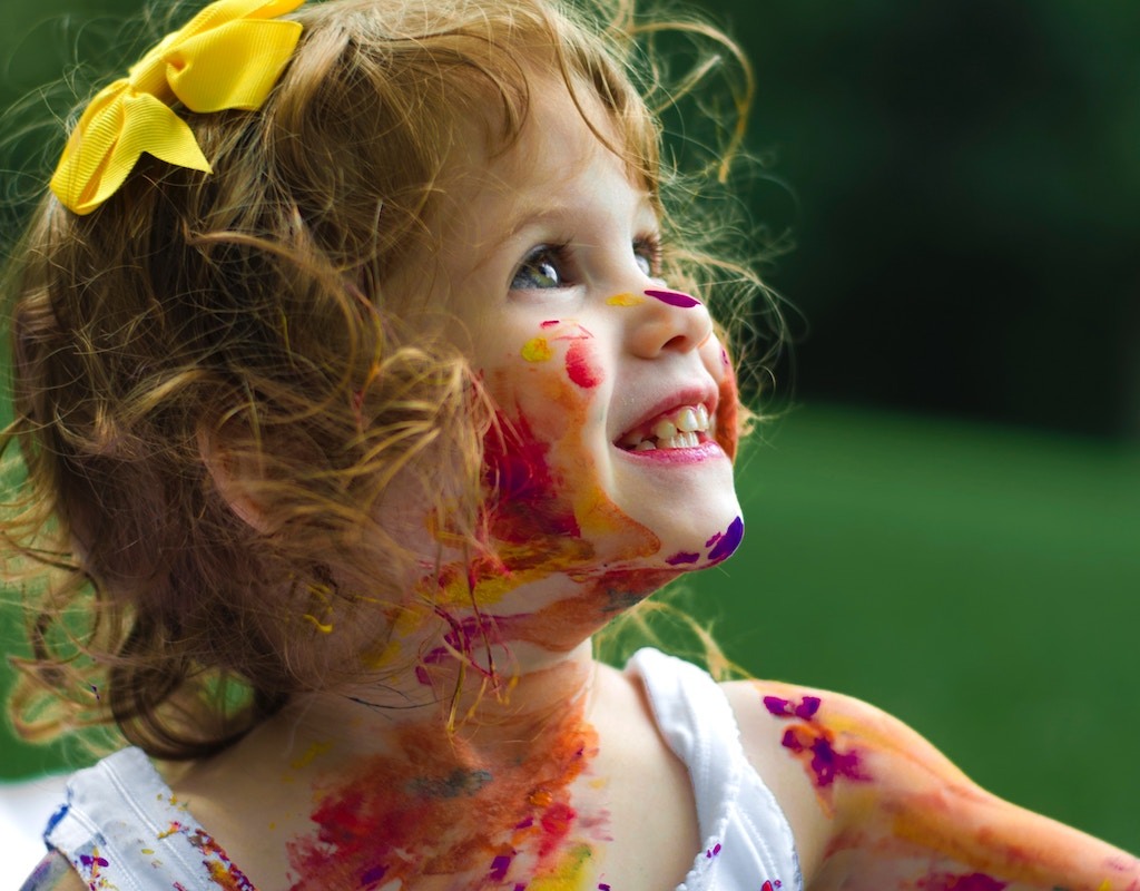 Young girl covered in brightly colored paint