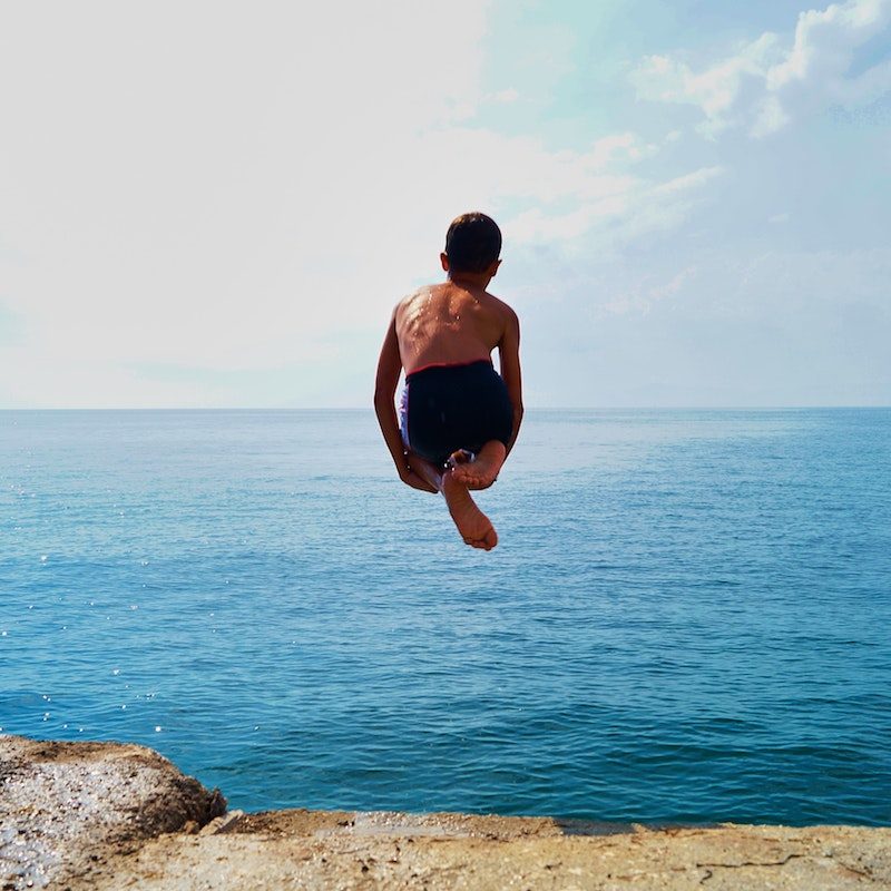 Young boy doing a cannonball into the ocean