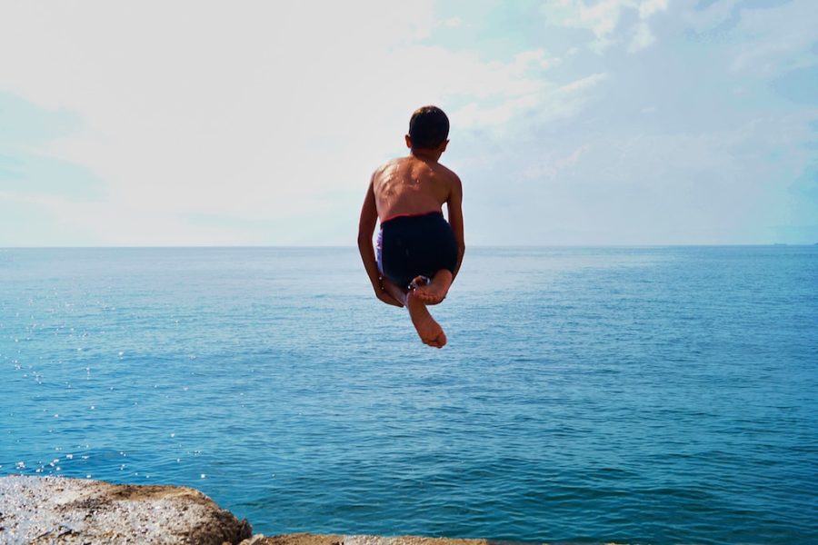 Young boy doing a cannonball into the ocean