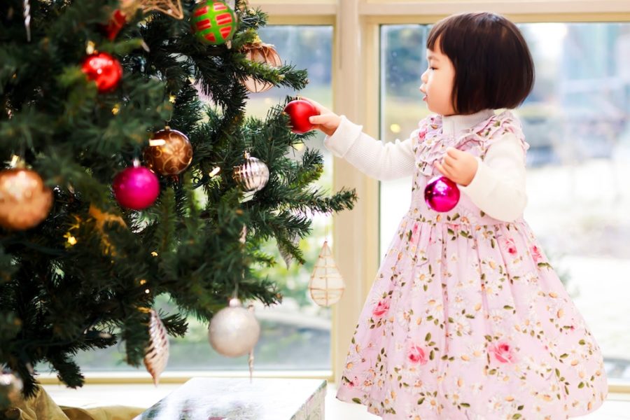 Little girl placing bulbs on a Christmas tree
