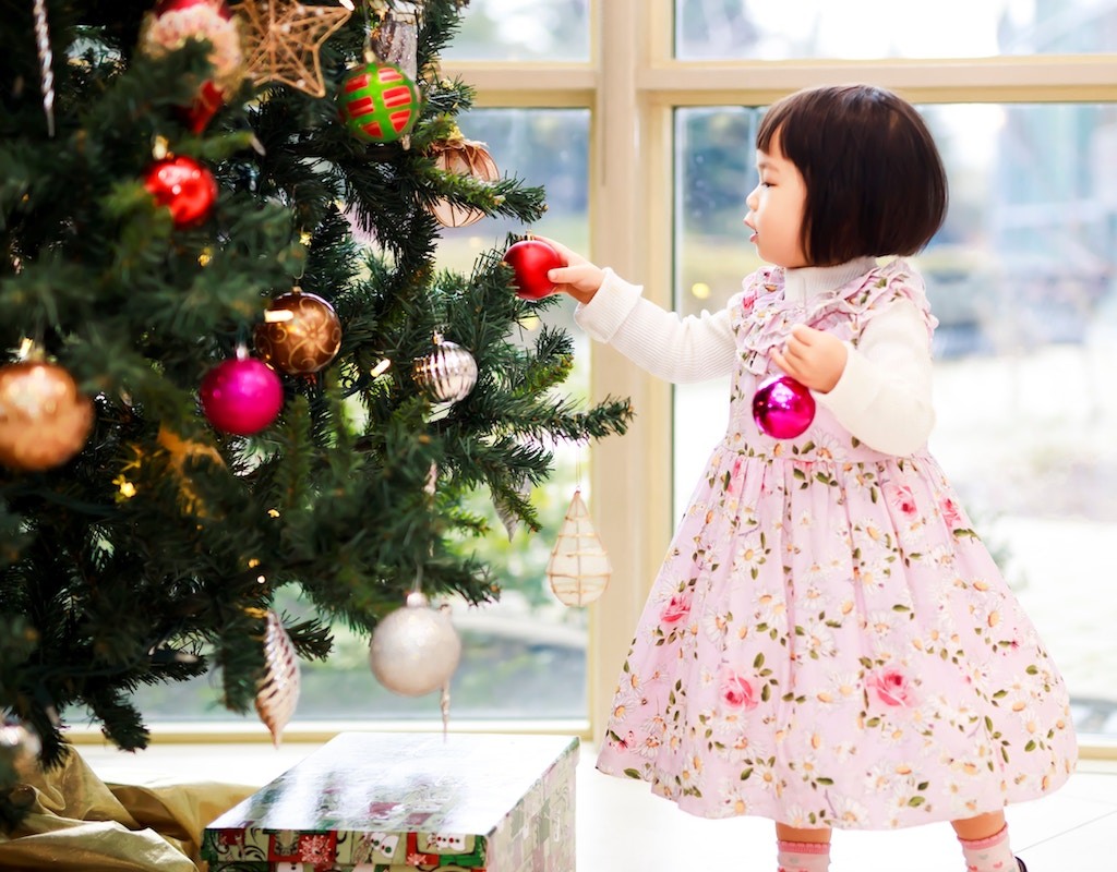 Little girl placing bulbs on a Christmas tree