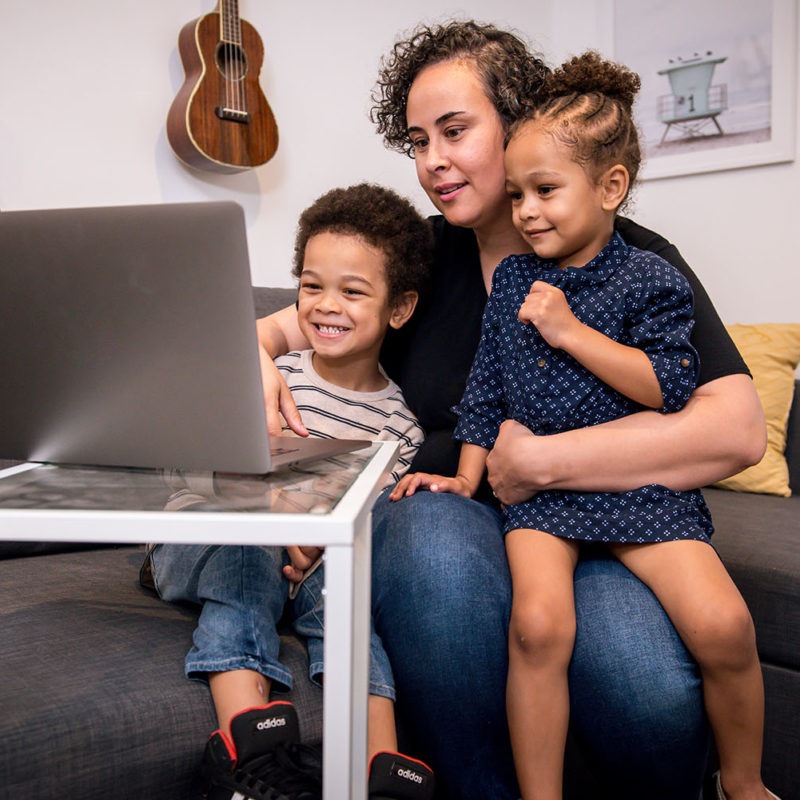 Mother, son and daughter sitting on a couch in front of a computer for a virtual visit